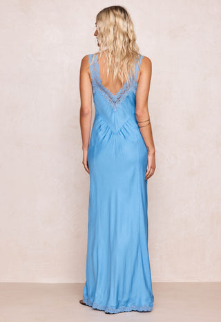 back-view-of-a-woman-wearing-a-blue-maxi-dress-with-lace-panels-against-a-beige-background