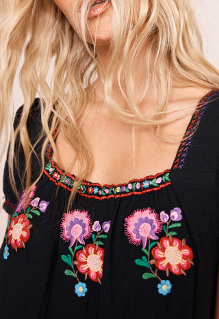 close-up-of-a-woman-wearing-a-black-embroidered-top-with-colorful-floral-embroidery-and-a-multicolor-embroidered-neckline