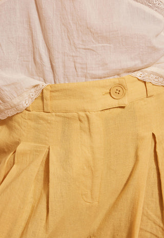 close-up-of-a-yellow-linen-pleated-skirt-paired-with-a-cream-colored-lace-trimmed-blouse