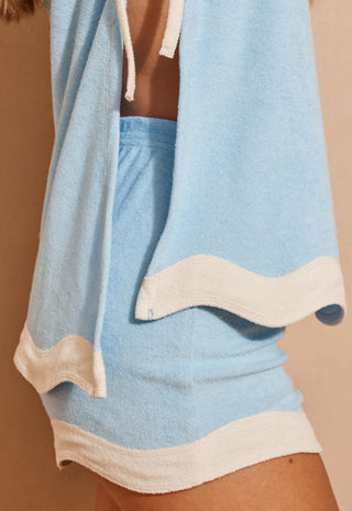 a-close-up-of-a-light-blue-and-cream-two-piece-lounge-set-worn-by-a-model-featuring-a-matching-top-and-shorts-with-wavy-cream-trim